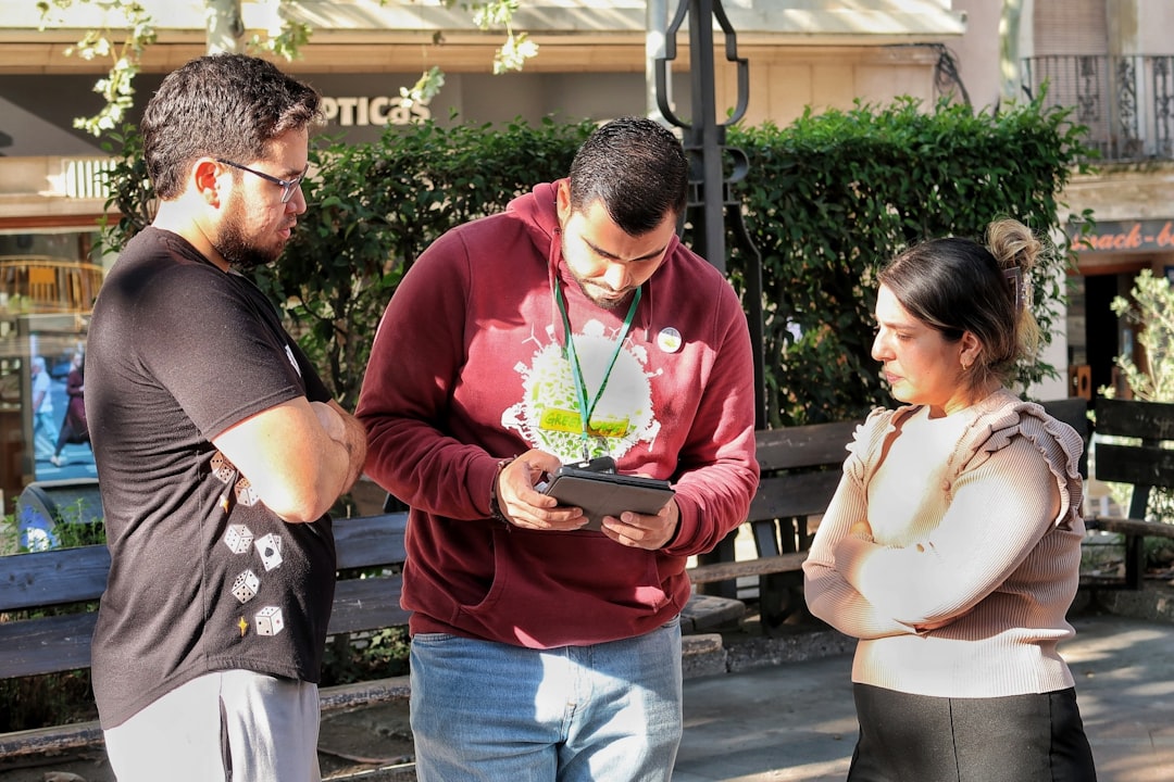 invisible systems. Three people looking at a tablet outdoors device outdoors